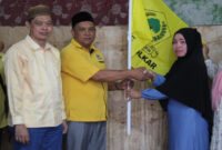 Sekretaris DPD Partai Golkar Kabupaten Lobar, Adi Subardi, S.H saat menyerahkan bendera Partai Golkar kepada Ketua terpilih PK Partai Golkar Kecamatan Lembar, Martinah.