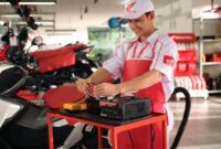 Petugas bengkel resmi AHASS saat mengecek aki motor milik konsumen Honda.